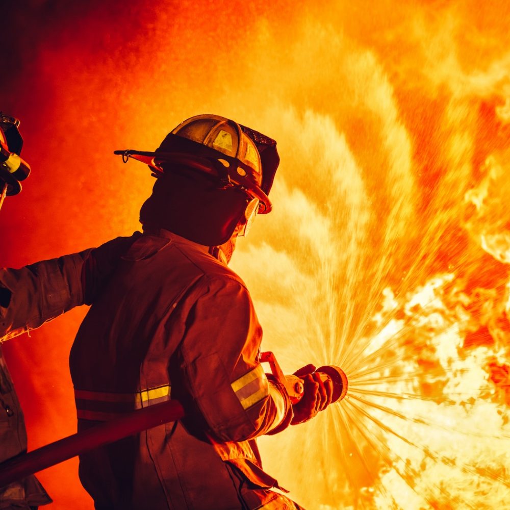 Fearless Firefighters Battling Blaze with Water and Extinguishers. Firefighters in Action, Extinguishing Fire with Teamwork and Courage. Intense Firefighting Training Exercise.